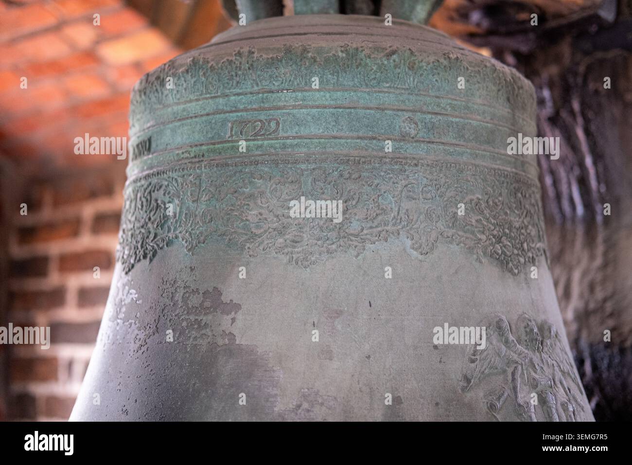 : Nahaufnahme einer antiken Bronzeglocke zeigt das Gussjahr 1729 und verzierte Blumenmuster. Stockfoto