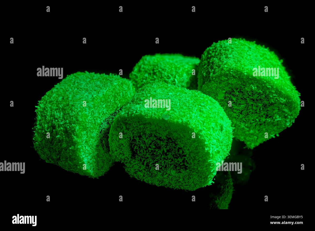 Eine Nahaufnahme mit kontrastreichen süßen türkischen Delikatessen (Lokum), die in leuchtendem Neongrün überzogen und mit feinen Kokosflocken bestäubt sind, Stockfoto