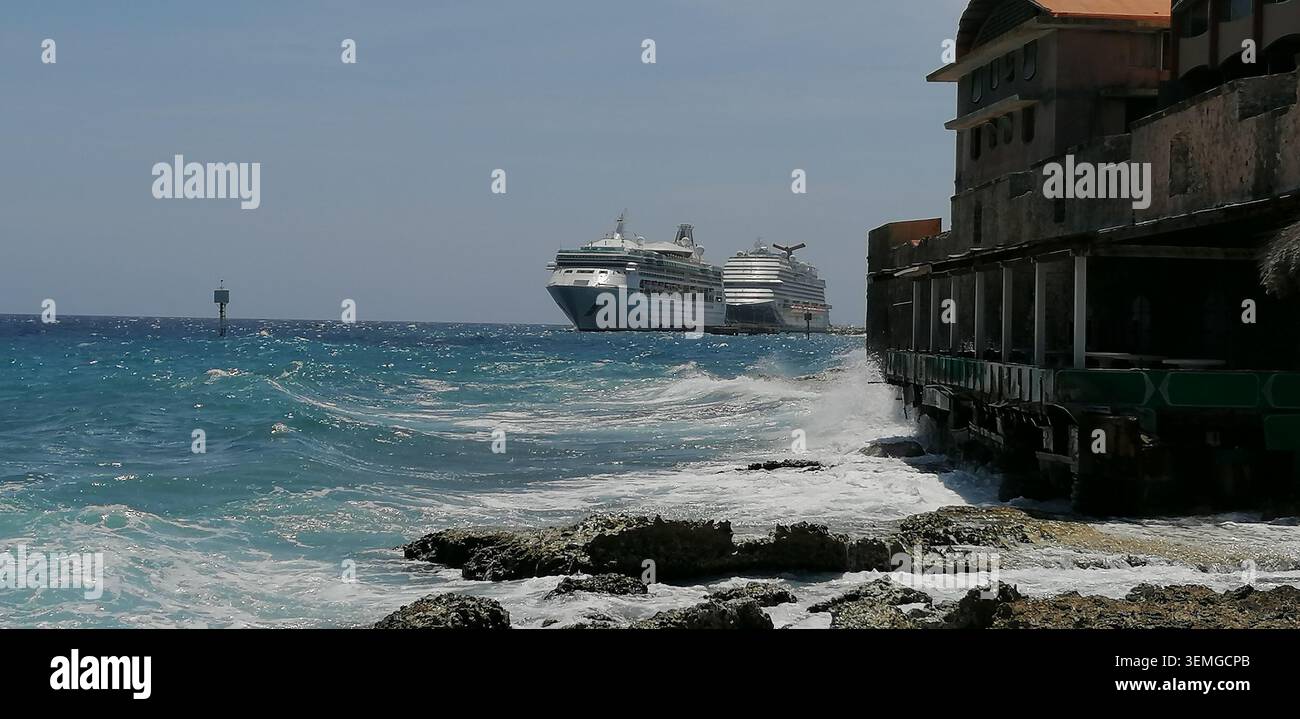Kreuzfahrtschiffe legen in Willemstad, Curacao, an, mit türkisfarbenem karibischem Wasser und einer zerklüfteten Küste an. - Smartphone-aufgenommenes Stockfoto