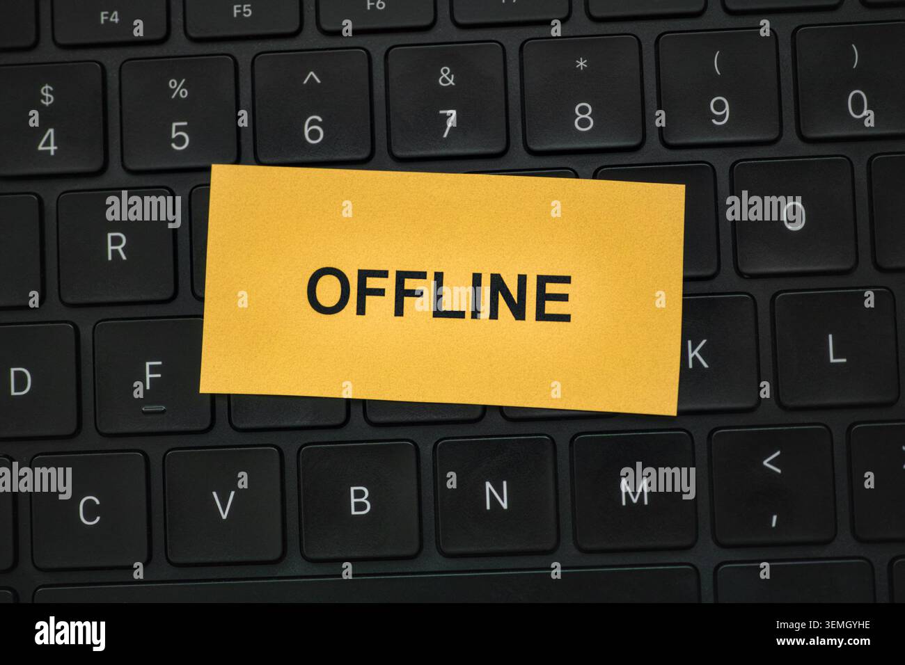 Eine gelbe Notiz mit dem eingegebenen Wort OFFLINE auf einer schwarzen Laptop-Tastatur. Nahaufnahme. Stockfoto
