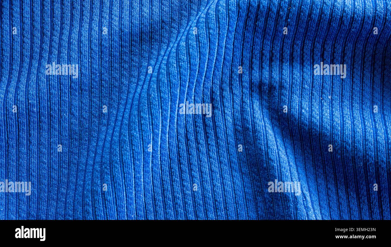 Abstrakte Nahaufnahme aus hellblauem Rippenstrick mit weichen Wellen und eleganten Falten Stockfoto