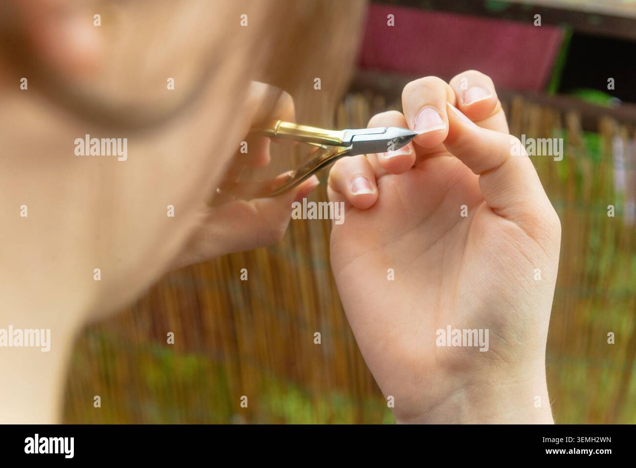 Makroaufnahme von weiblichen Händen bei der präzisen Nagelpflege vor Terrassenkulisse Stockfoto