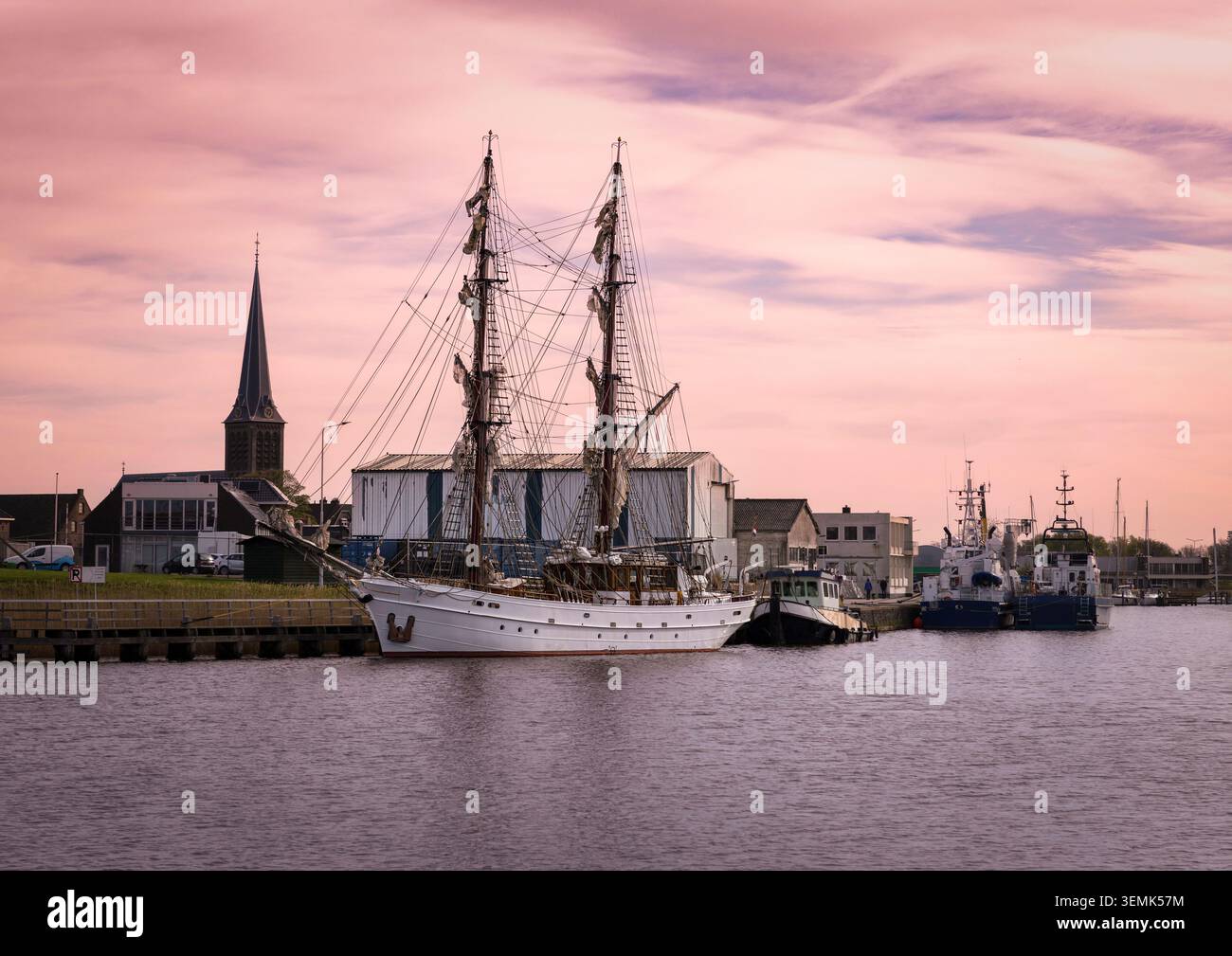 Traditionelle Segelboote liegen im Hafen von Lemmer, Niederlande, mit einem Teil der historischen Stadt im Hintergrund. Ein friedliches maritimes s Stockfoto
