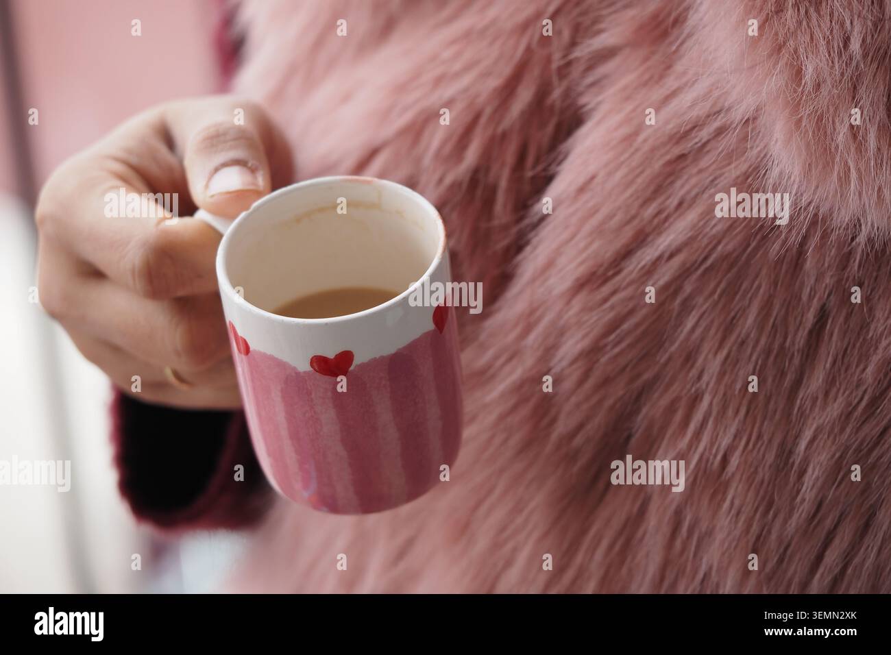 Genießen Sie Kaffee in einer rosafarbenen Tasse in einem zwanglosen Moment Stockfoto
