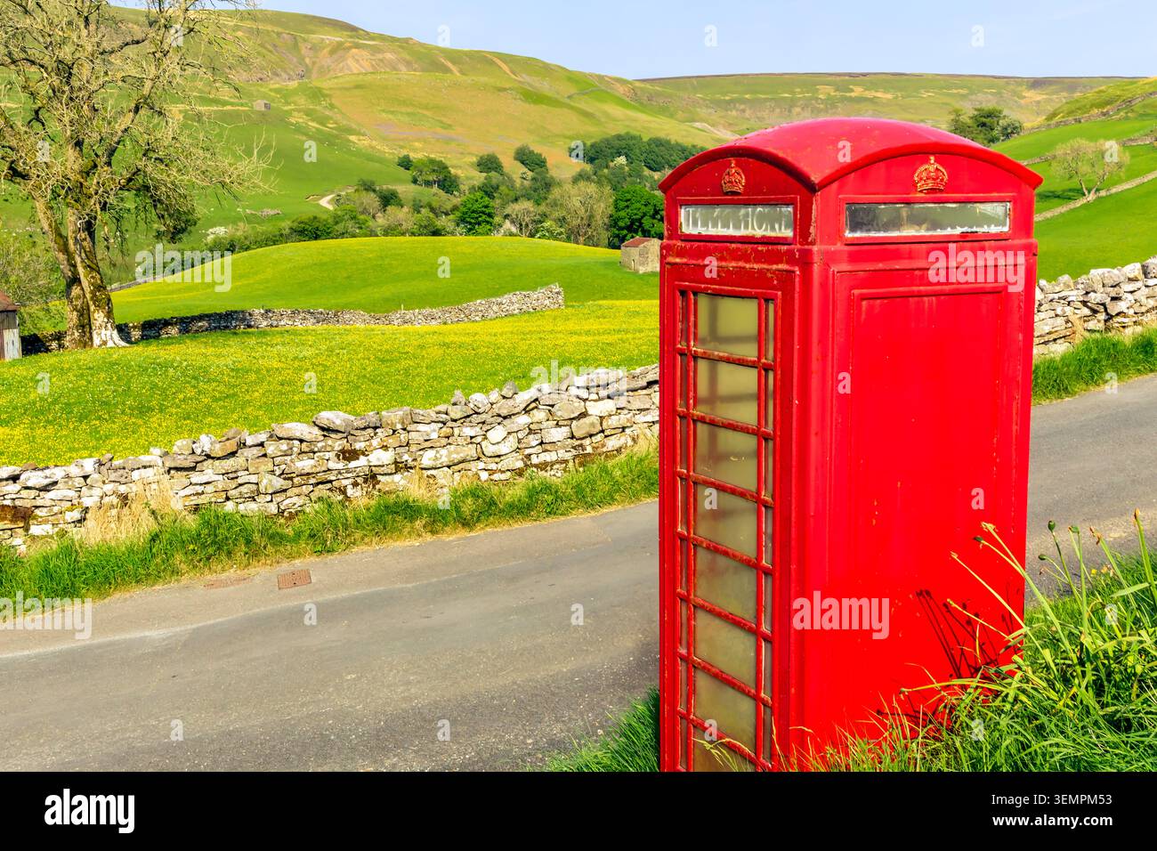 Das ländliche Dorf Keld in Swaledale, Yorkshire Dales, Großbritannien, mit gelben Wildblumenwiesen und legendären, altmodischen roten Telefonzellen und Stockfoto