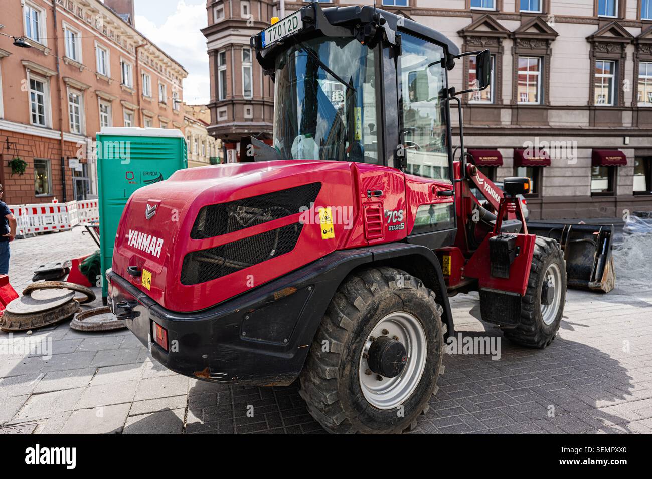 Vilnius, Litauen - 01. Juni 2026: Roter Kompaktlader von Yanmar parkt auf einer Kopfsteinpflasterstraße in Vilnius, Litauen, während Straßeninstandhaltungsarbeiten. Stockfoto