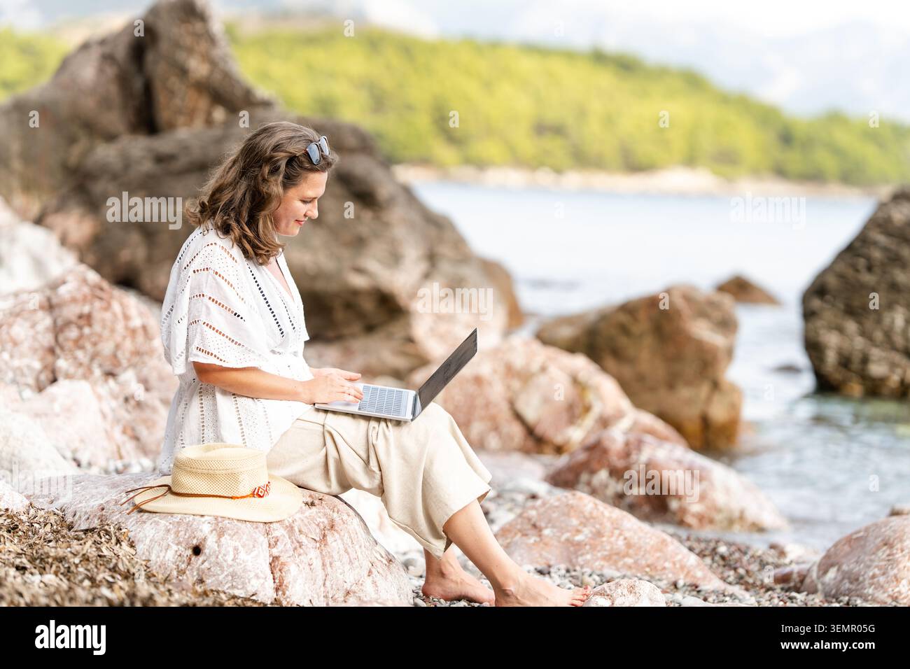 Weibliche Freiberuflerin mit Laptop an der Küste Stockfoto