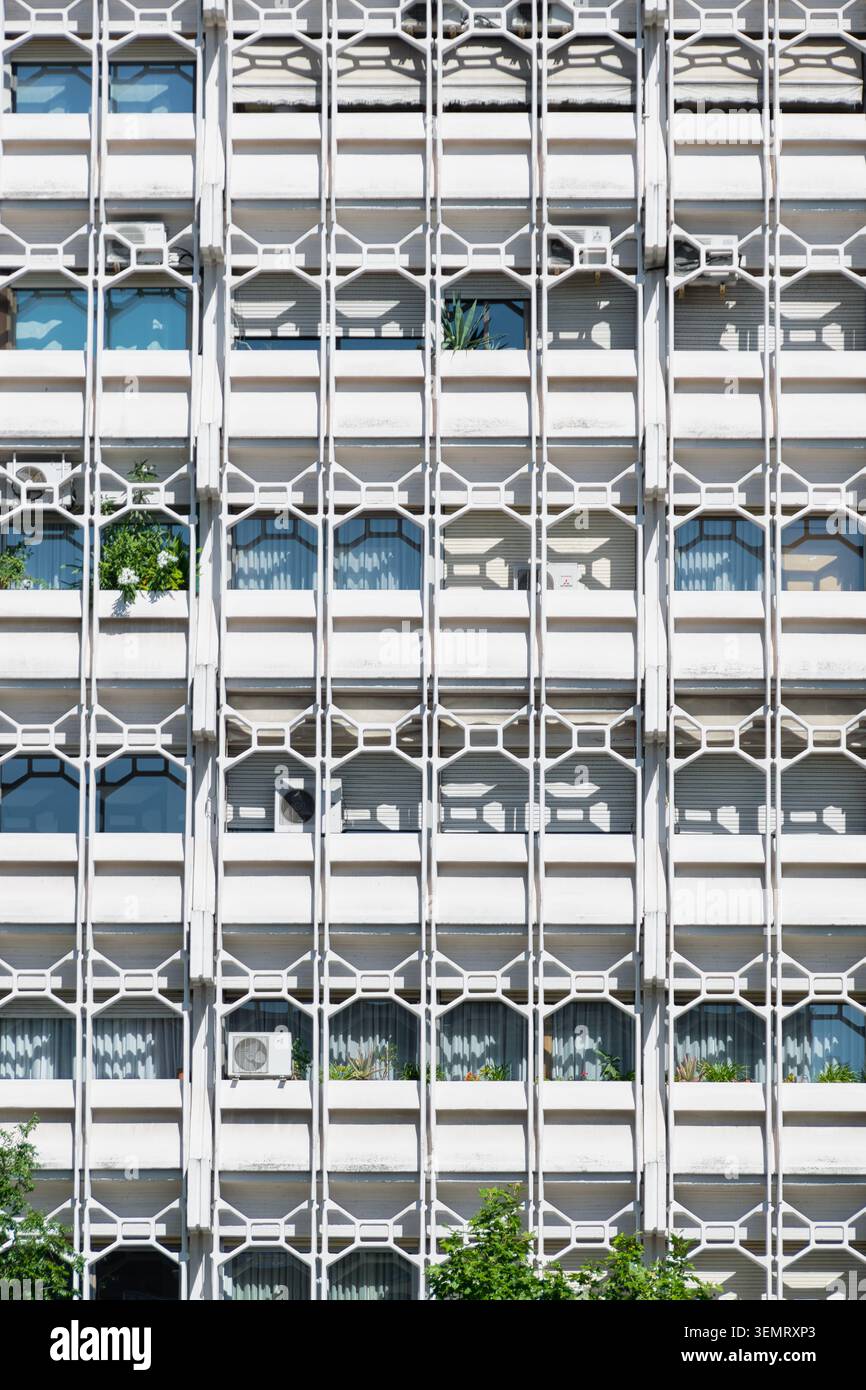 Moderne Wohnhausfassade mit sich wiederholenden geometrischen Balkonen, Fenstern und Pflanzen in Madrid, Spanien. Stockfoto