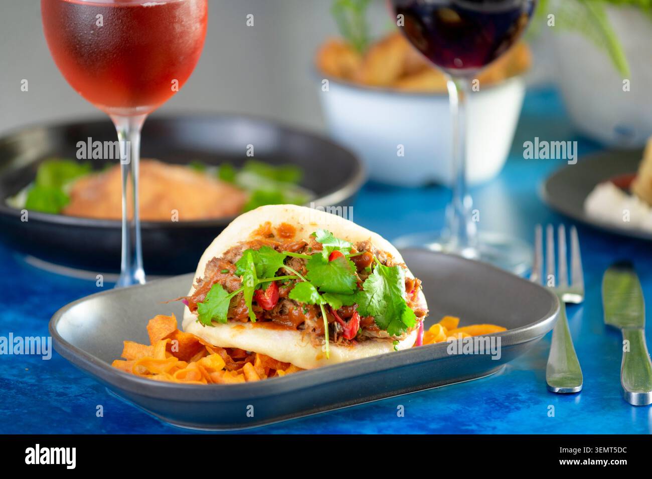 Herzhaftes Bao-Brötchen gefüllt mit aromatischem Fleisch und frischen Kräutern, serviert mit süßen Kartoffelbrötchen Stockfoto