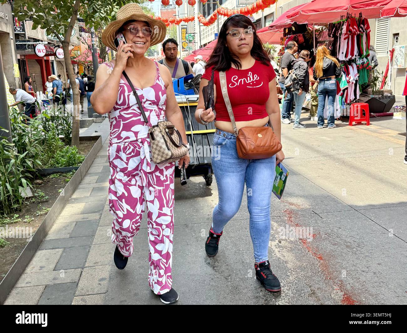 Zwei Frauen spazieren entlang der Calle Dolores in Chinatown, dem historischen Zentrum von Mexiko City, mit Geschäften und Straßenverkäufern im Hintergrund Stockfoto