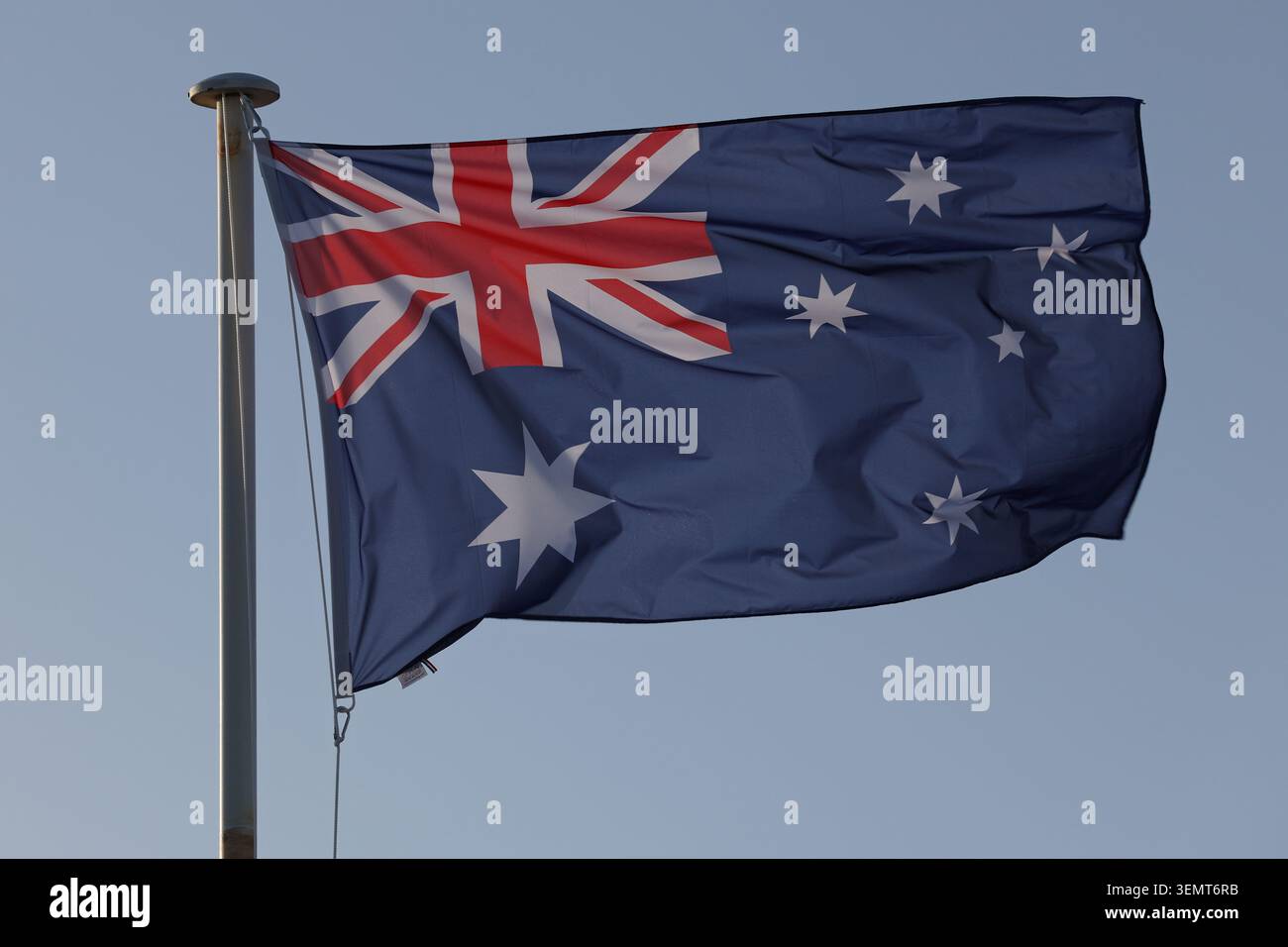 Die australische Nationalflagge fliegt im Wind vor einem blauen Himmel. Stockfoto