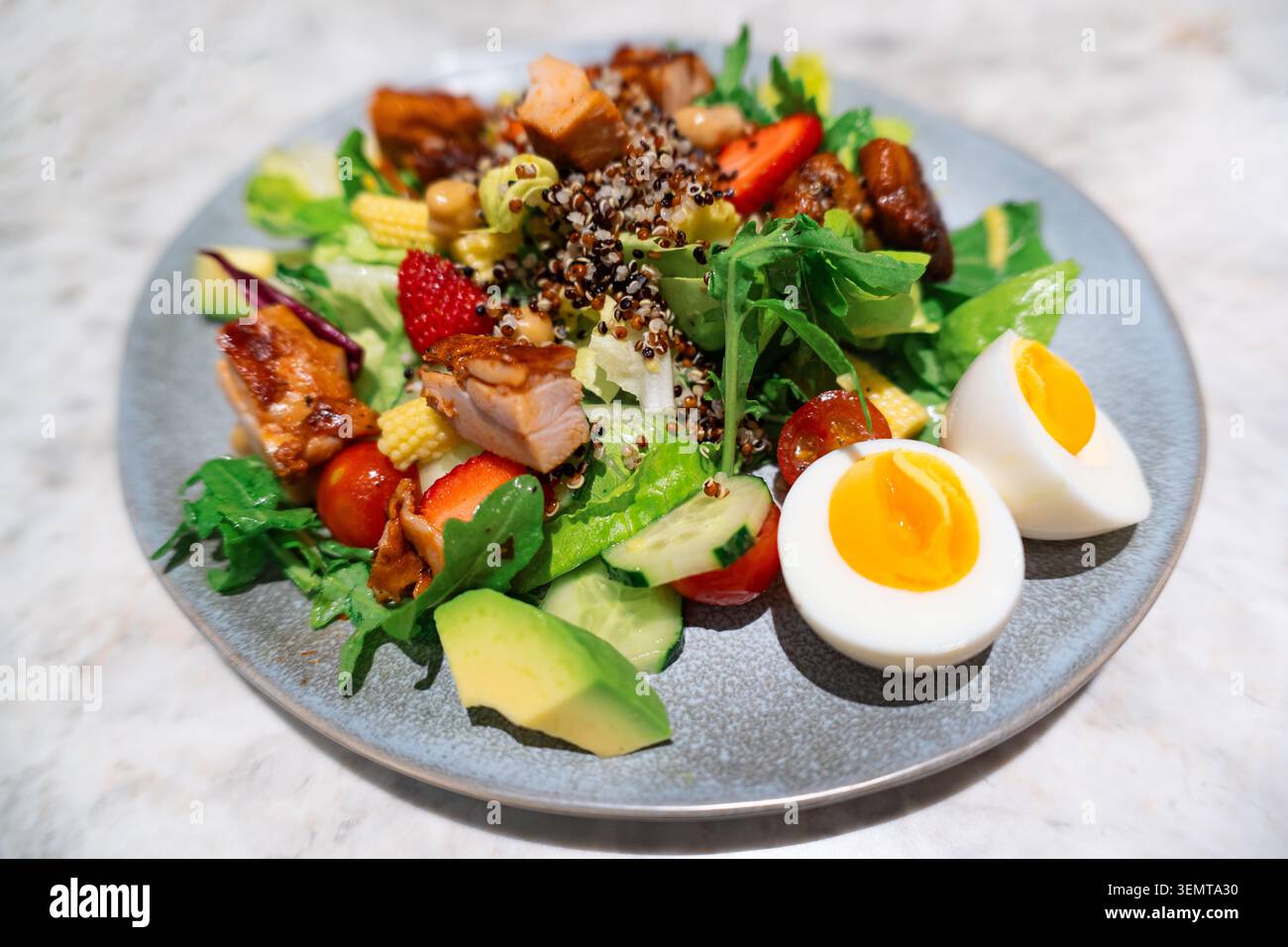 Frischer Quinoa-Salat mit gegrilltem Huhn, Erdbeeren, Avocado, hart gekochtem Ei und gemischtem Gemüse Stockfoto
