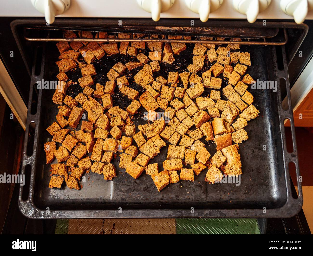 Blick von oben auf in Würfel geschnittene Roggenbrotscheiben auf dem Backofen in der ländlichen Küche Stockfoto