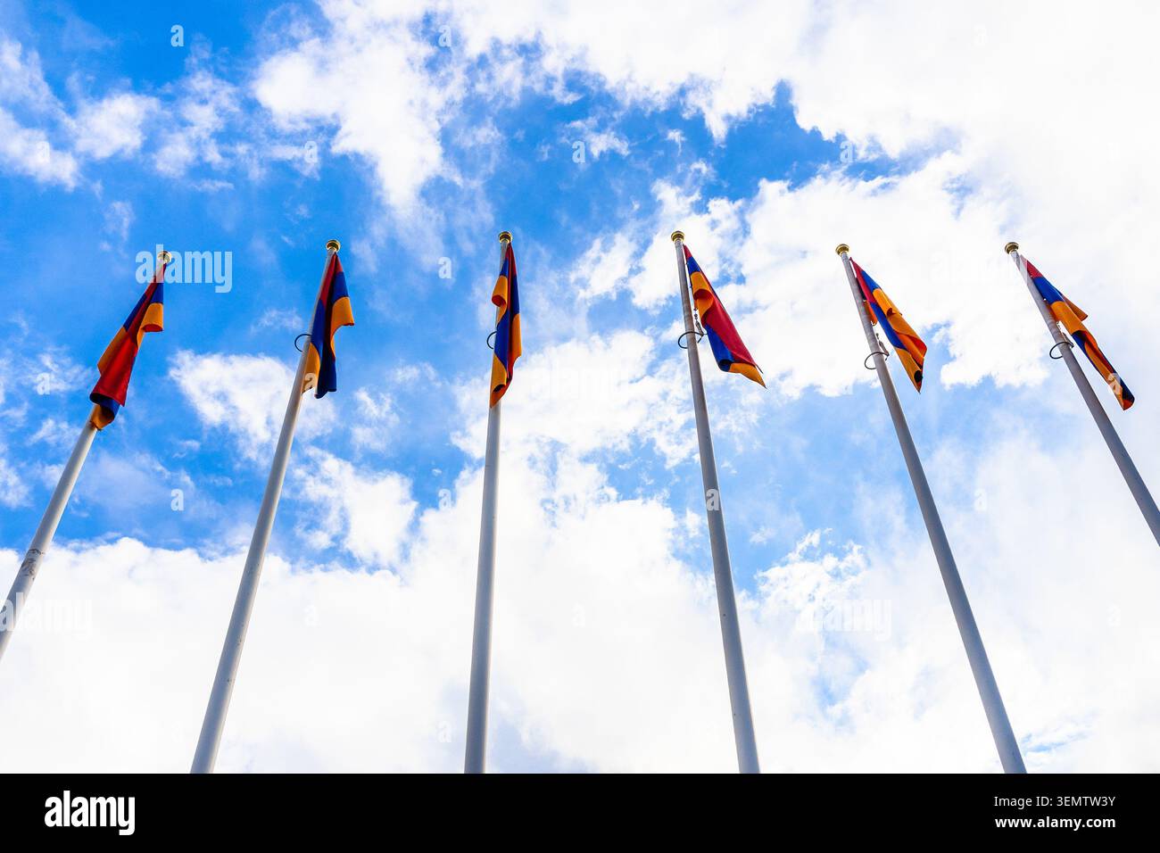Unteransicht der Fahnenmasten mit Nationalflaggen der Republik Armenien und blauer Himmel mit weißen Wolken im Hintergrund in Vanadzor Stadt in Armenien an Stockfoto