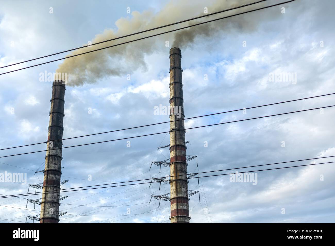 Fabrikschornsteine, Die Industrielle Luftverschmutzung Verursachen. Hohe Fabrikschornsteine geben Rauch in einen bewölkten Himmel ab, was industrielle Verschmutzung und Energie zeigt Stockfoto