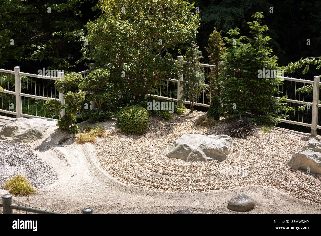Japanischer Zen-Garten mit geharkten Kiesmustern, Ziersträuchern und Natursteinelementen Stockfoto