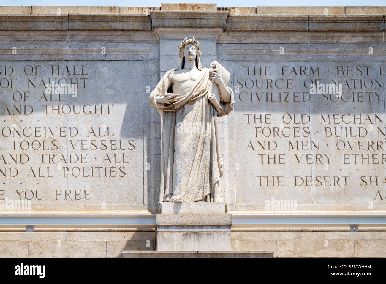 Apollo Vorstellung Allegorische Figur Washington Union Station Friesinschrift | WASHINGTON D.C., Vereinigte Staaten — Apollo, der Vorstellungskraft symbolisiert, steht zwischen zwei lesbaren Granitinschriften an der Südfassade der Union Station, Teil von Louis Saint-Gaudens's Friesreihe "Der Fortschritt der Eisenbahn." Von Harvard-Präsident Charles W. Eliot komponiert, würdigt der Text die Vorstellungskraft, die "alle Werkzeuge, Schiffe und den Handel und alle Politik" erdacht hat, und die Mechanik, die "den Ozean" überwunden und "den Äther selbst menschliche Gedanken tragen lässt" — eine Rhetorik, die das Eisenbahnzeitalter als den Gipfel der Zivilisation darstellt. Stockfoto