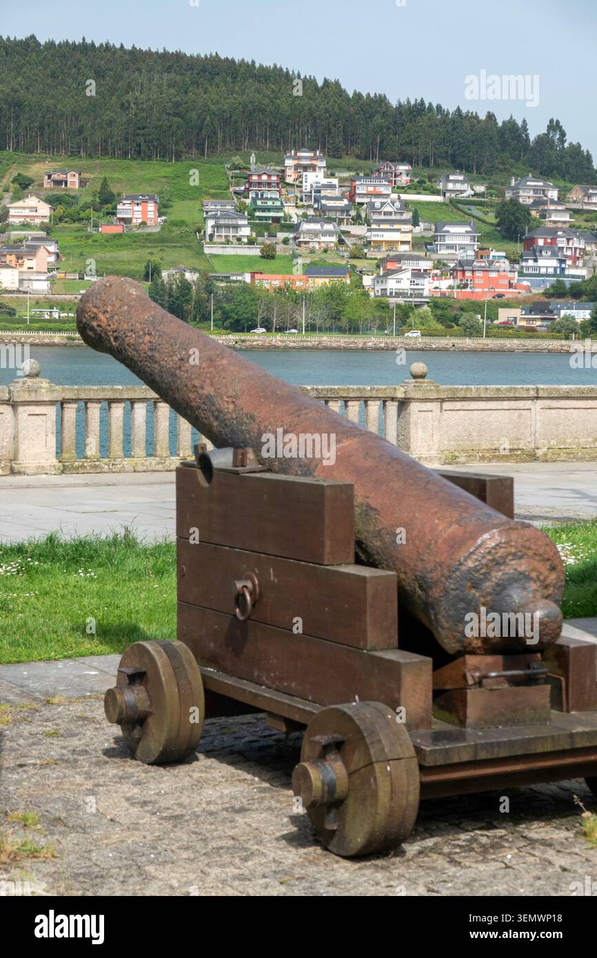 Alte rostige Kanone auf einem Holzwagen mit Blick auf die Mündung und die Hügel in Viveiro, Lugo, Galicien, Spanien. Stockfoto