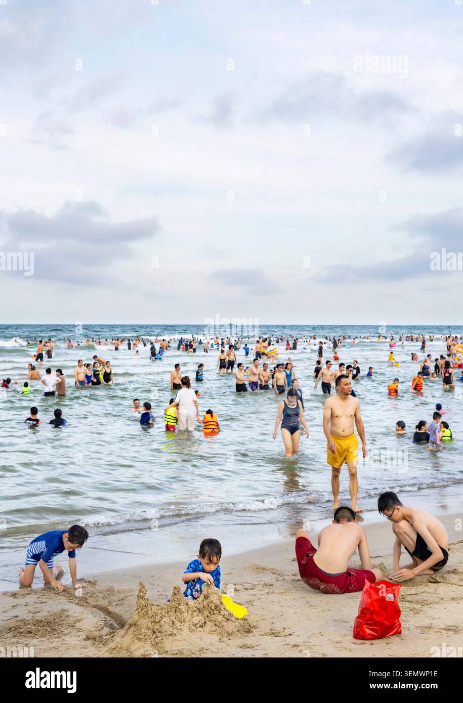 Vietnam-18. Juni 2025: Bei Sonnenuntergang kommen viele Urlauber und Einheimische, um den breiten weißen Strand zu genießen, wo Kinder im Sand spielen und Familienspaß haben Stockfoto