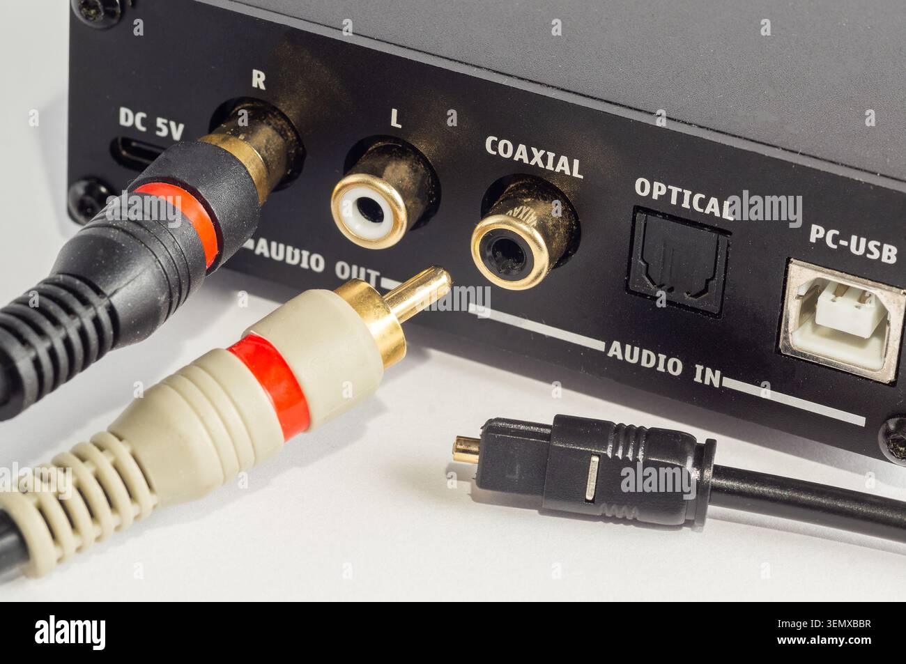Nahaufnahme der Cinch-Anschlüsse, die an ein Audiogerät und ein optisches Kabel angeschlossen sind. Stockfoto