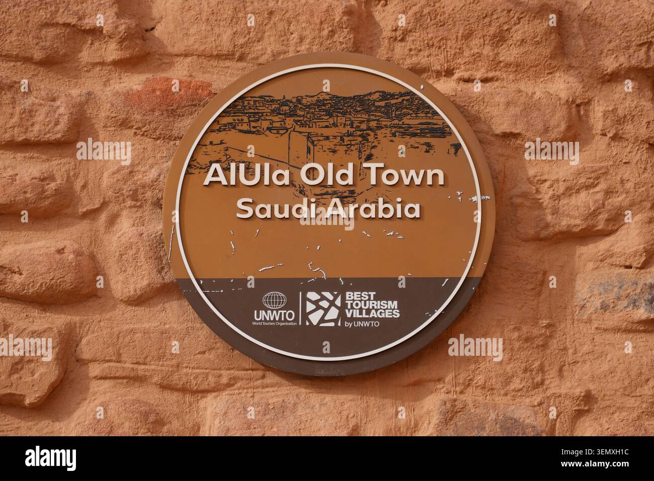 Offizielle Gedenktafel der UNWTO „Best Tourism Villages“ an einer Steinmauer in der Altstadt von Alula, Saudi-Arabien Stockfoto