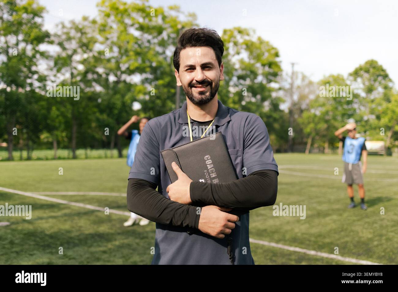 Arabischer Fußballtrainer Lächelt Mit Spielern Auf Dem Outdoor-Fußballfeld Stockfoto