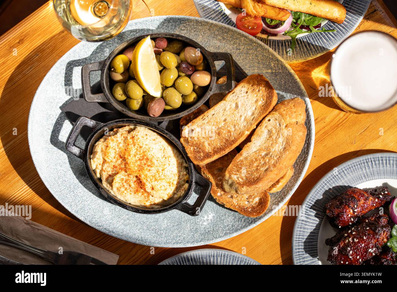 Köstliche Mezze-Platte mit warmen Dips und Oliven auf einem rustikalen Holztisch Stockfoto