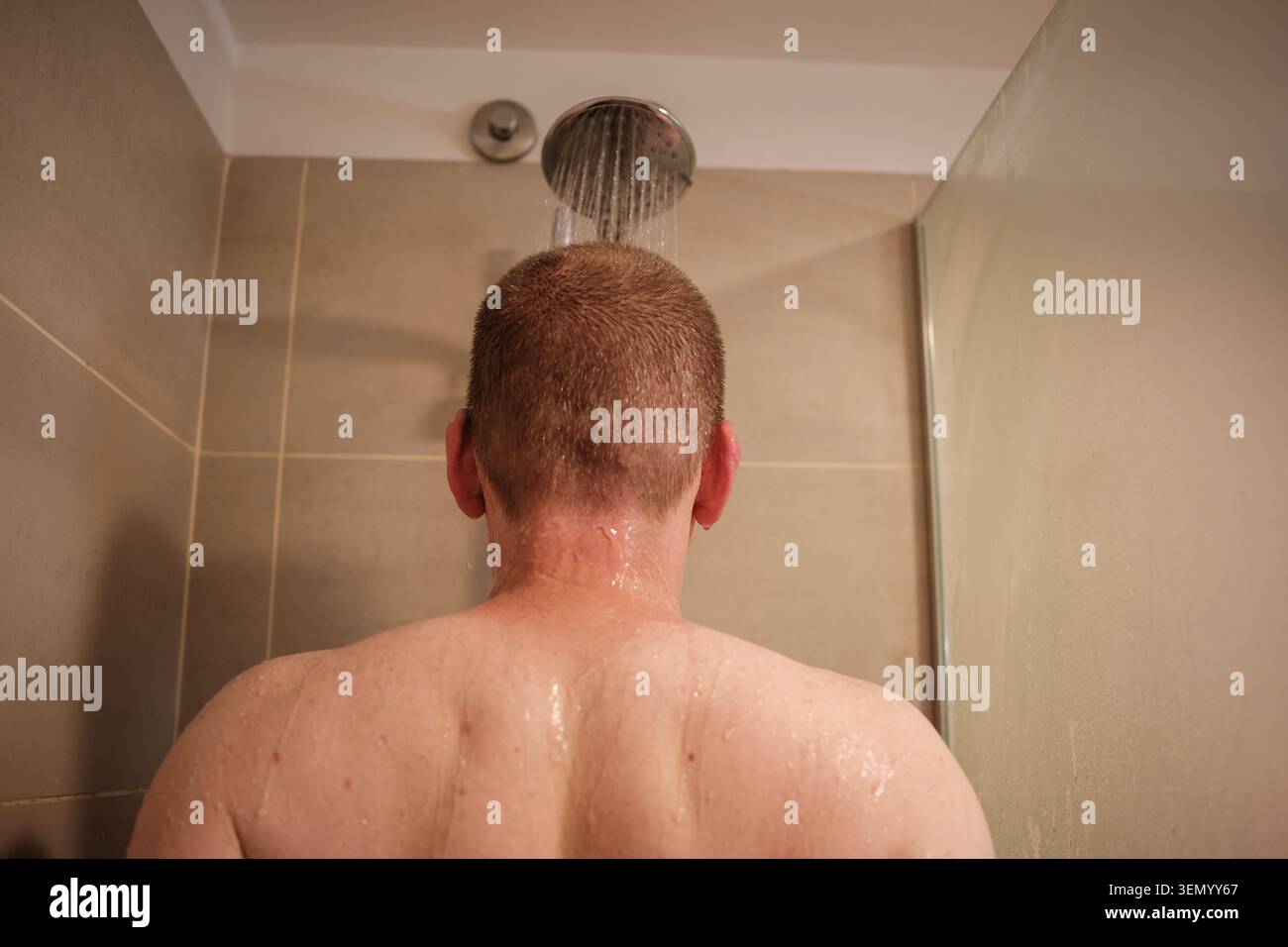 Mann, der mit Wasser aus dem Duschkopf wäscht, tägliche Hygiene praktiziert Stockfoto