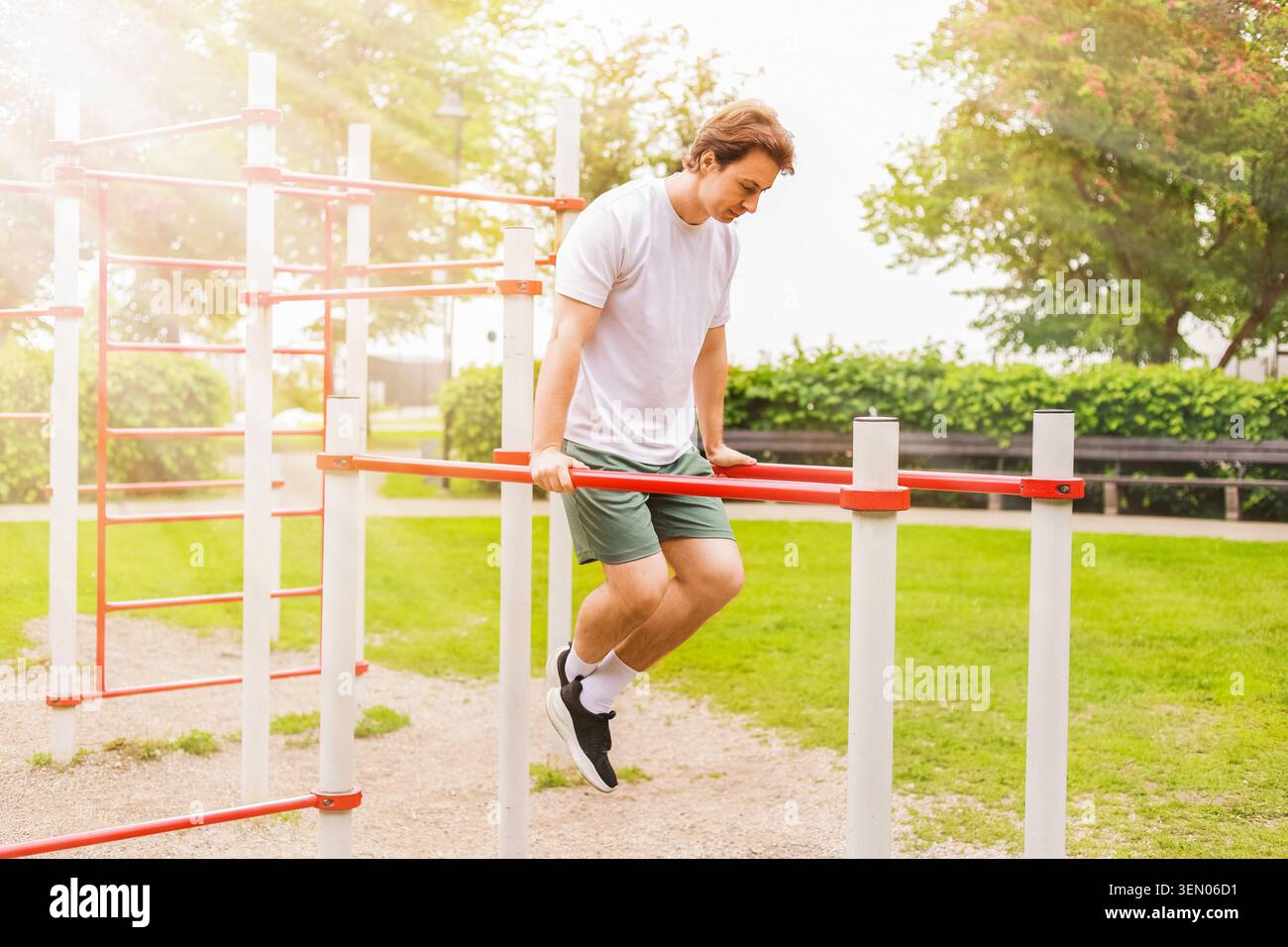 Mann, der auf einem Sportplatz im Freien Dips an parallelen Bars durchführt. Calisthenics Fitness-Training im Park an einem sonnigen Tag. Hochwertige Fotos Stockfoto