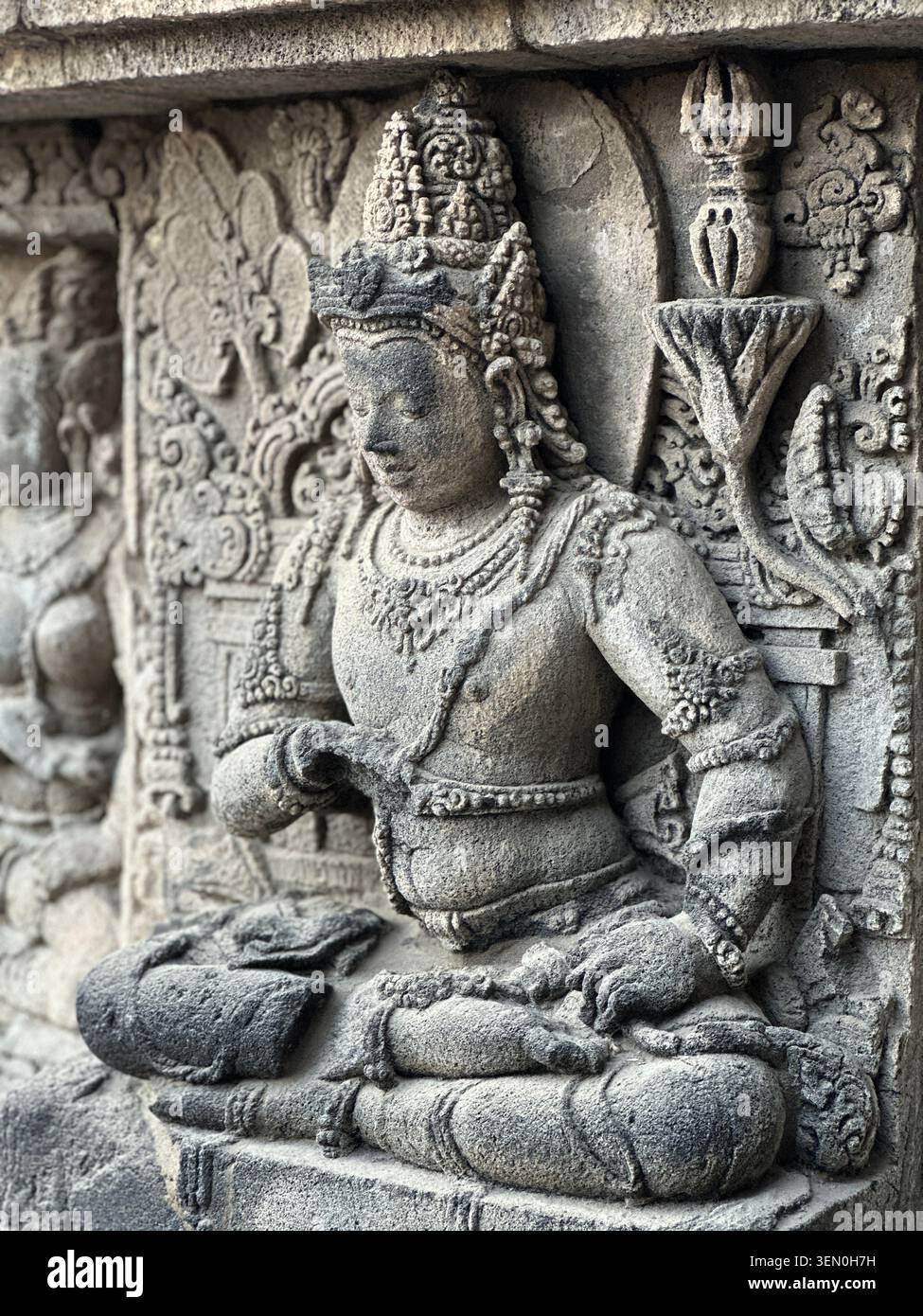 Steinkalt gelassen: ein antikes geschnitztes Relief einer sitzenden Gottheit im Borobudur-Tempel, Zentral-Java, Indonesien - Smartphone-aufgenommenes Stockfoto