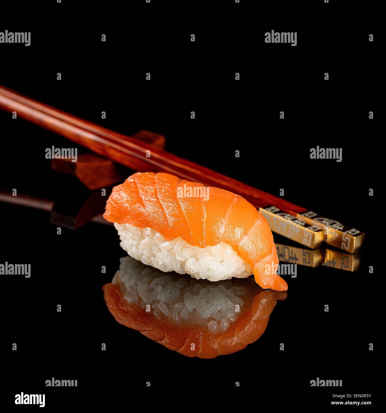 Frisches Lachs-Nigiri-Sushi auf glänzend schwarzer, reflektierender Oberfläche mit Holzstäbchen und Spiegelreflektion. Stockfoto