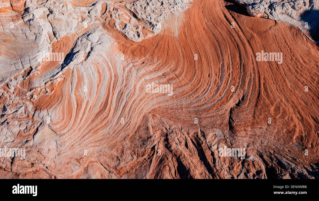 Aus der Vogelperspektive leuchtende orange und weiße Felsformationen mit markanten Wellenmustern. Marmor Canyon, Arizona, USA Stockfoto