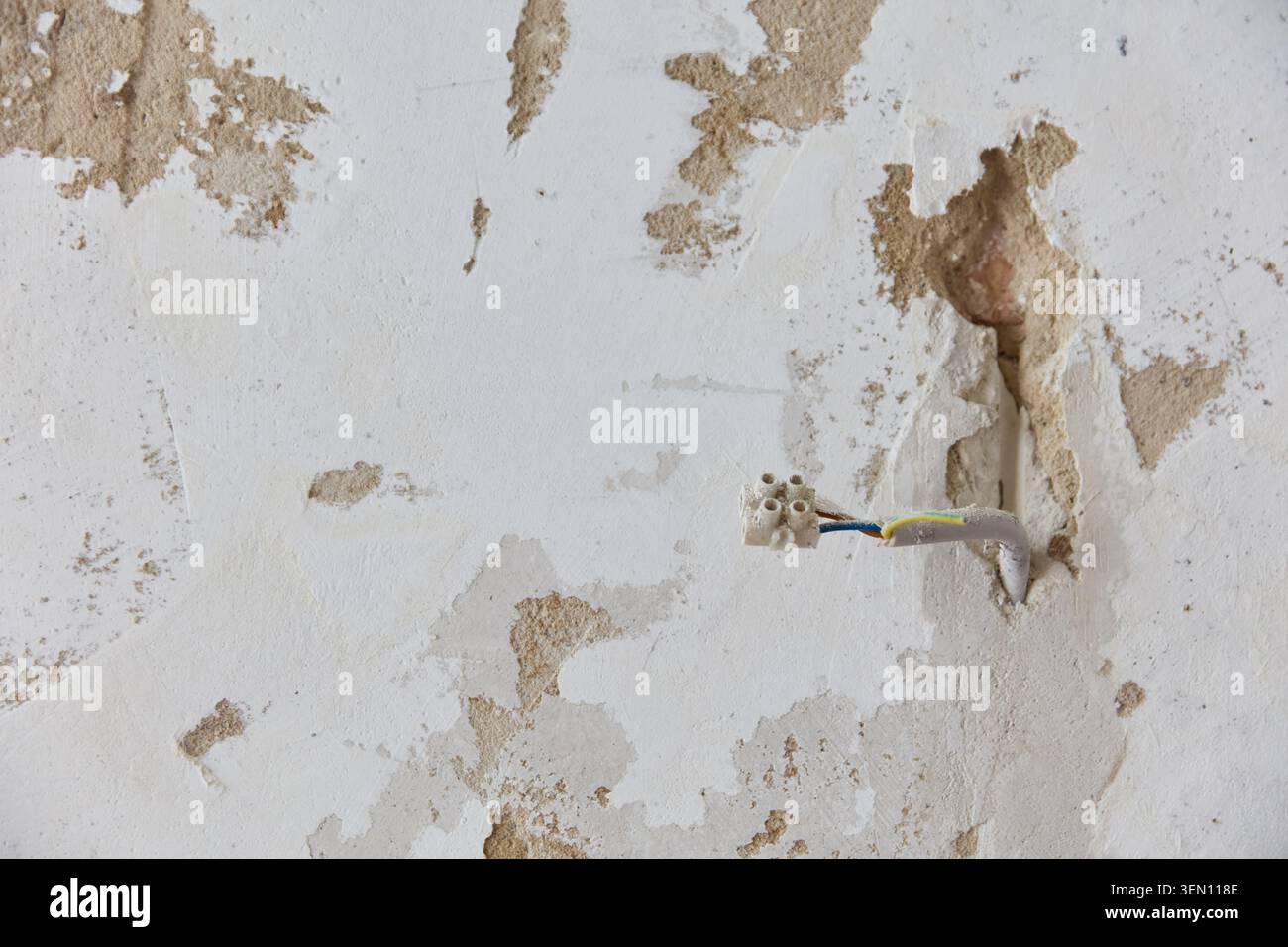 Dabei handelt es sich um ein Renovierungsprojekt in einer alten Berliner Wohnung, bei dem freiliegende Stromkabel an einer beschädigten Wand sichtbar sind. Es veranschaulicht die Konstruktion, Stockfoto
