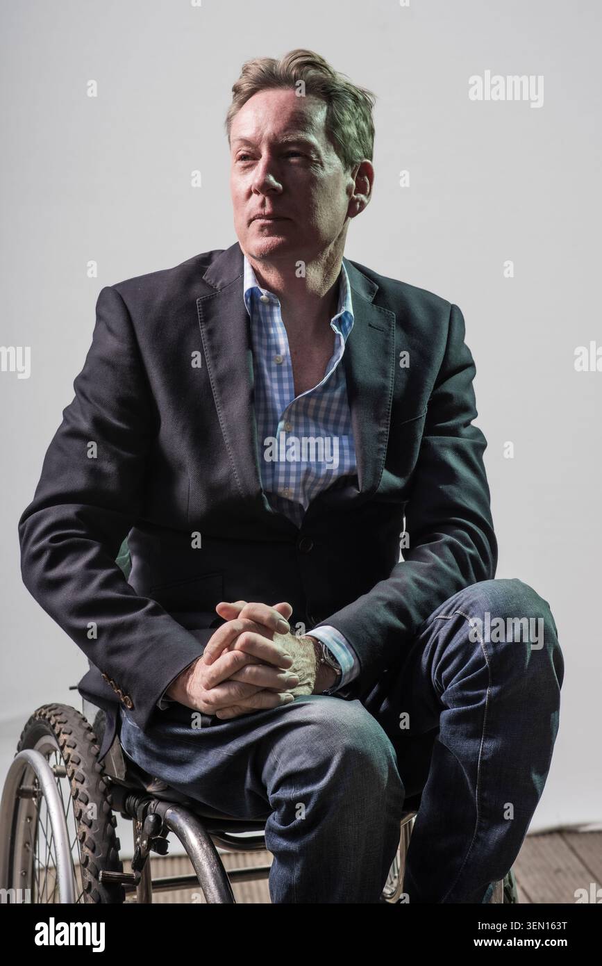 Frank Gardener sitzt im Rollstuhl in einer einfachen Inneneinrichtung. Er trägt eine Anzugsjacke und ein lässiges Hemd. Er hat einen ernsthaften Blick während der Pos Stockfoto