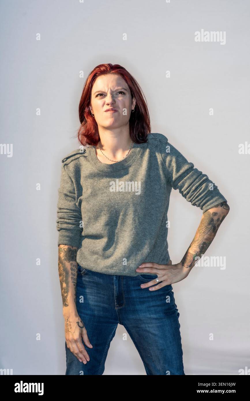 Jack Monroe steht mit einer starken Haltung und einem ernsten Gesicht vor einem einfachen Hintergrund. Sie trägt einen grauen Pullover und eine blaue Jeans, während sie Multip zeigt Stockfoto