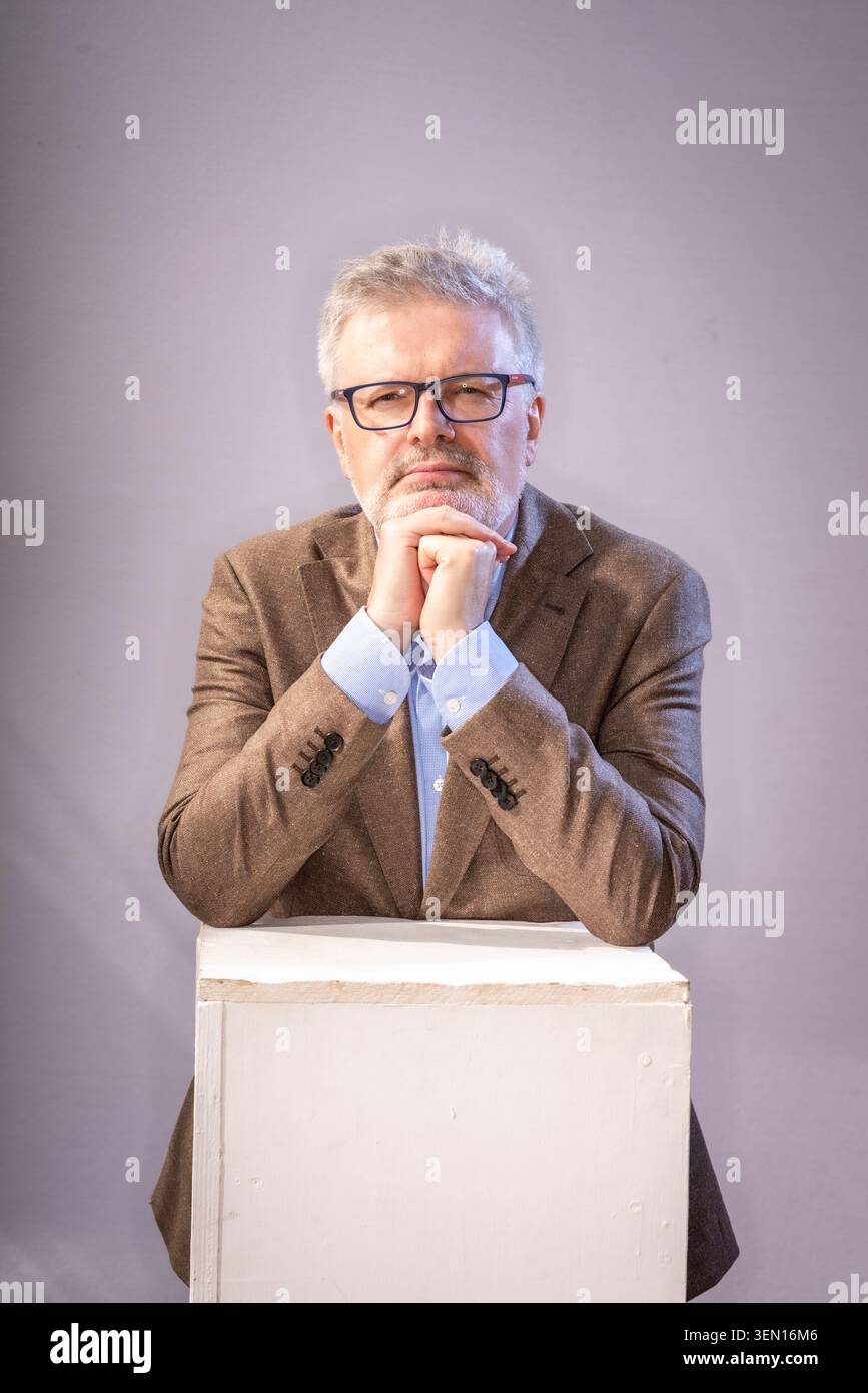 Der Komponist der Klassik-Musik James MacMillan steht mit den Händen, die auf einem weißen Block zusammengelegt sind. Er sieht nachdenklich und ernst aus. Stockfoto