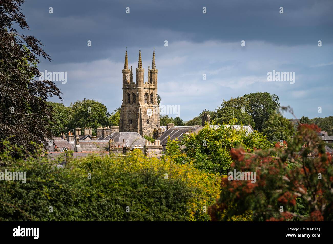 Breiter Blick auf die Landschaft mit Blick auf die historische Dachlinie des Dorfes Tideswell, eingebettet hinter grünen Hecken mit dem majestätischen Kirchturm Stockfoto