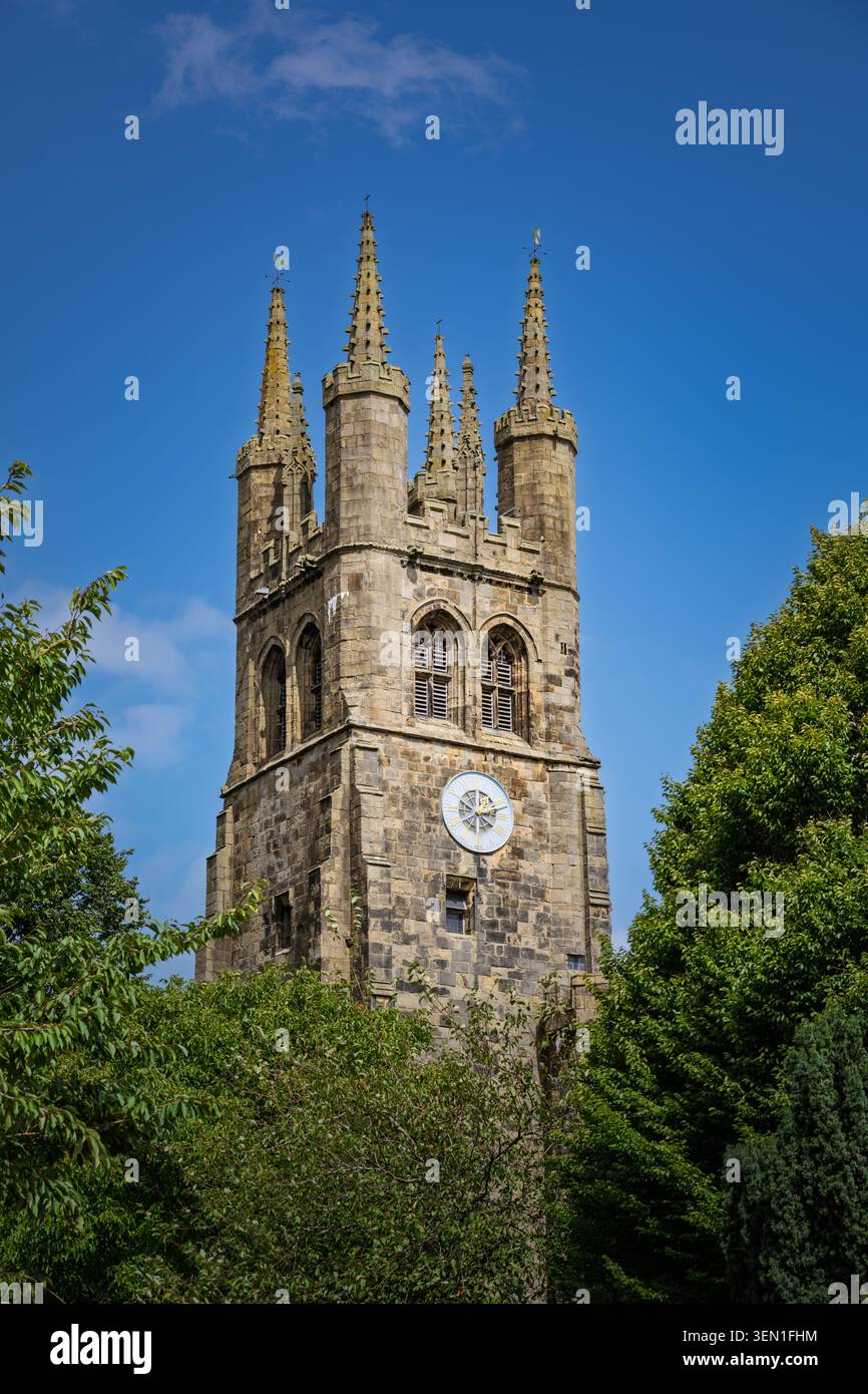 Enge vertikale, flache Ansicht mit Blick auf die kunstvollen Steindetails und dekorativen Zinnen des mittelalterlichen Glockenturms an der Tideswell Church Stockfoto