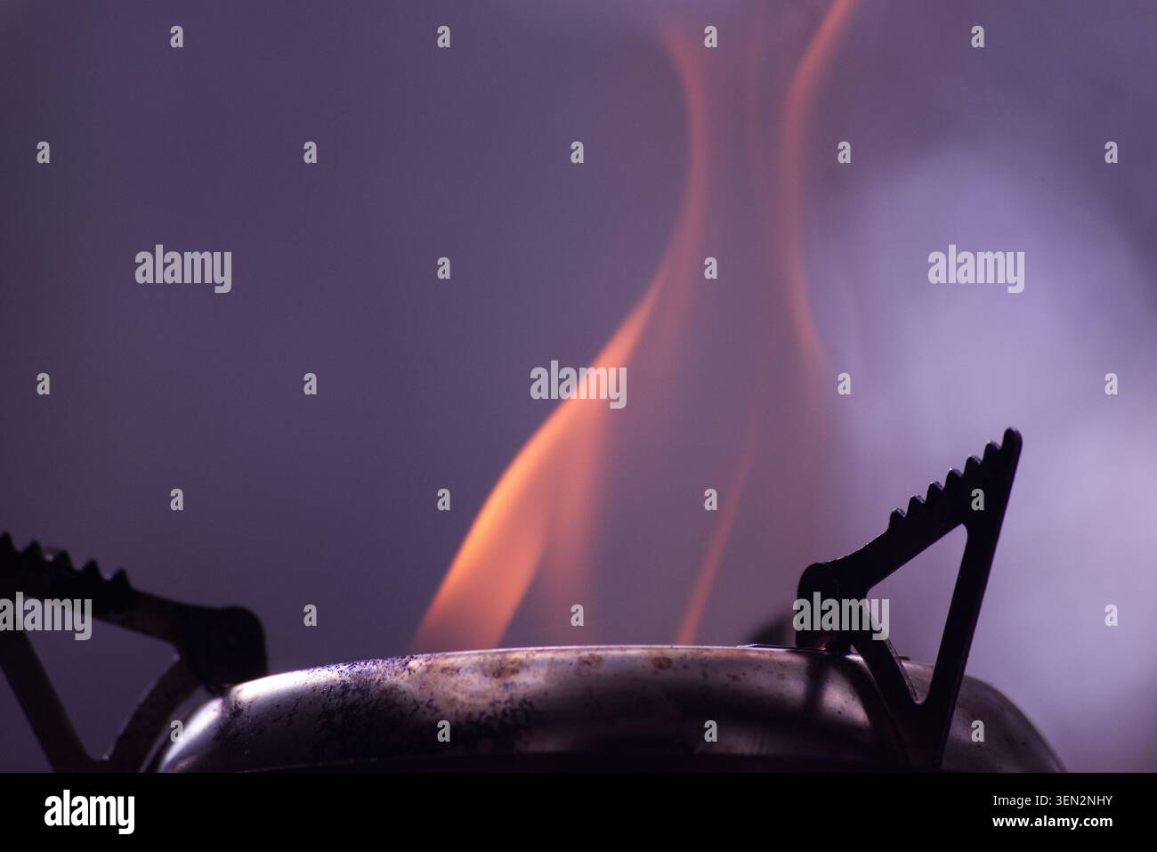 Gut benutzter tragbarer Holzofen, der Holz verbrennt, mit einer großen roten Flamme, die aus der Kammer hervorbricht. Kohlen für einen schnellen gegrillten Snack im Freien Stockfoto