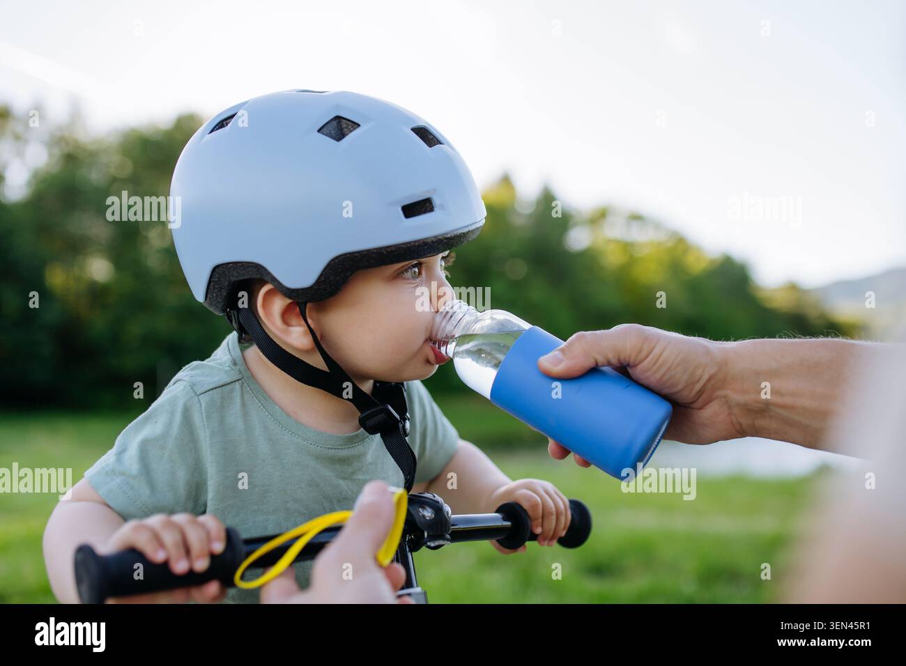 Vater gibt dem Sohn des Kleinkindes Wasser während einer Radpause im Freien. Stockfoto