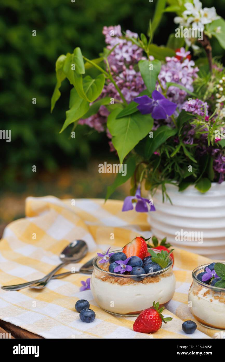 Close Up Käsekuchen Desserttassen mit frischen Beeren und essbaren Blumen Stockfoto