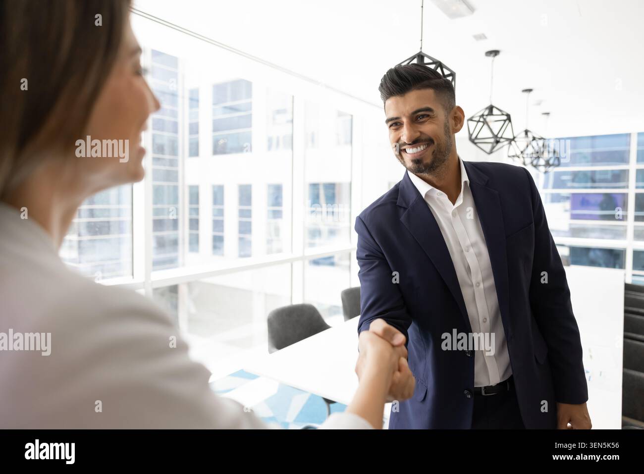 Selbstbewusster indischer Geschäftsmann im Anzug, der der Kollegin die Hand schüttelt Stockfoto