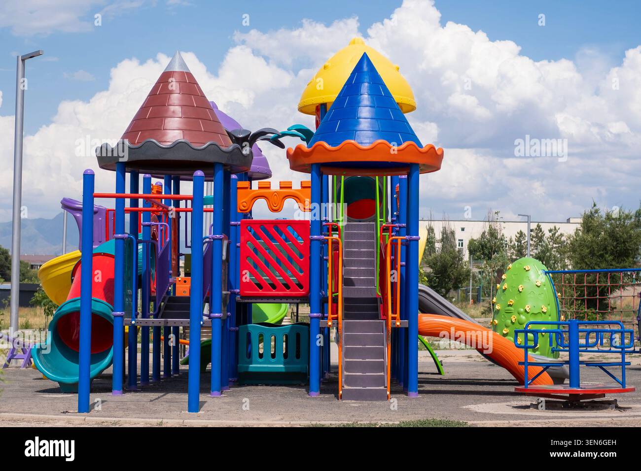 Farbenfroher Kinderspielplatz mit Rutschen, Klettergerüsten und Spielgeräten in einem Outdoor Park an einem sonnigen Tag unter blauem Himmel mit Wolken. Stockfoto