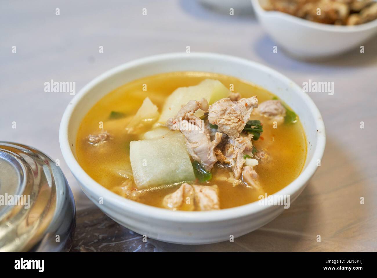 Authentische Seongju Fasansuppe mit gekochtem Rettich und zartem Geflügel, serviert in weißen Keramikschalen, die regionale kulinarische Traditionen widerspiegeln Stockfoto