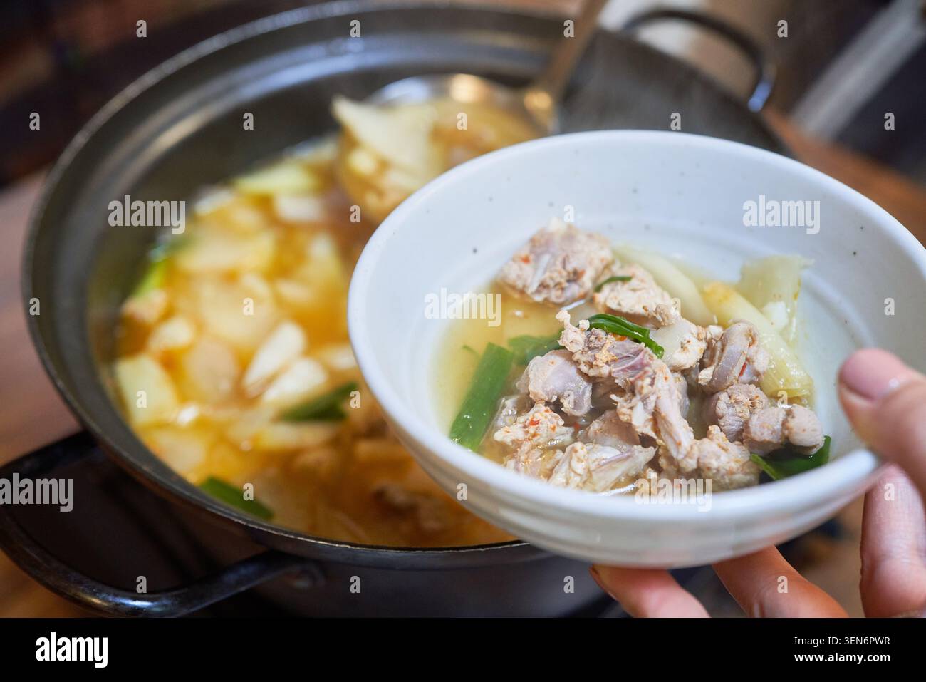 Authentische Seongju Fasansuppe mit gekochtem Rettich und zartem Geflügel, serviert in weißen Keramikschalen, die regionale kulinarische Traditionen widerspiegeln Stockfoto