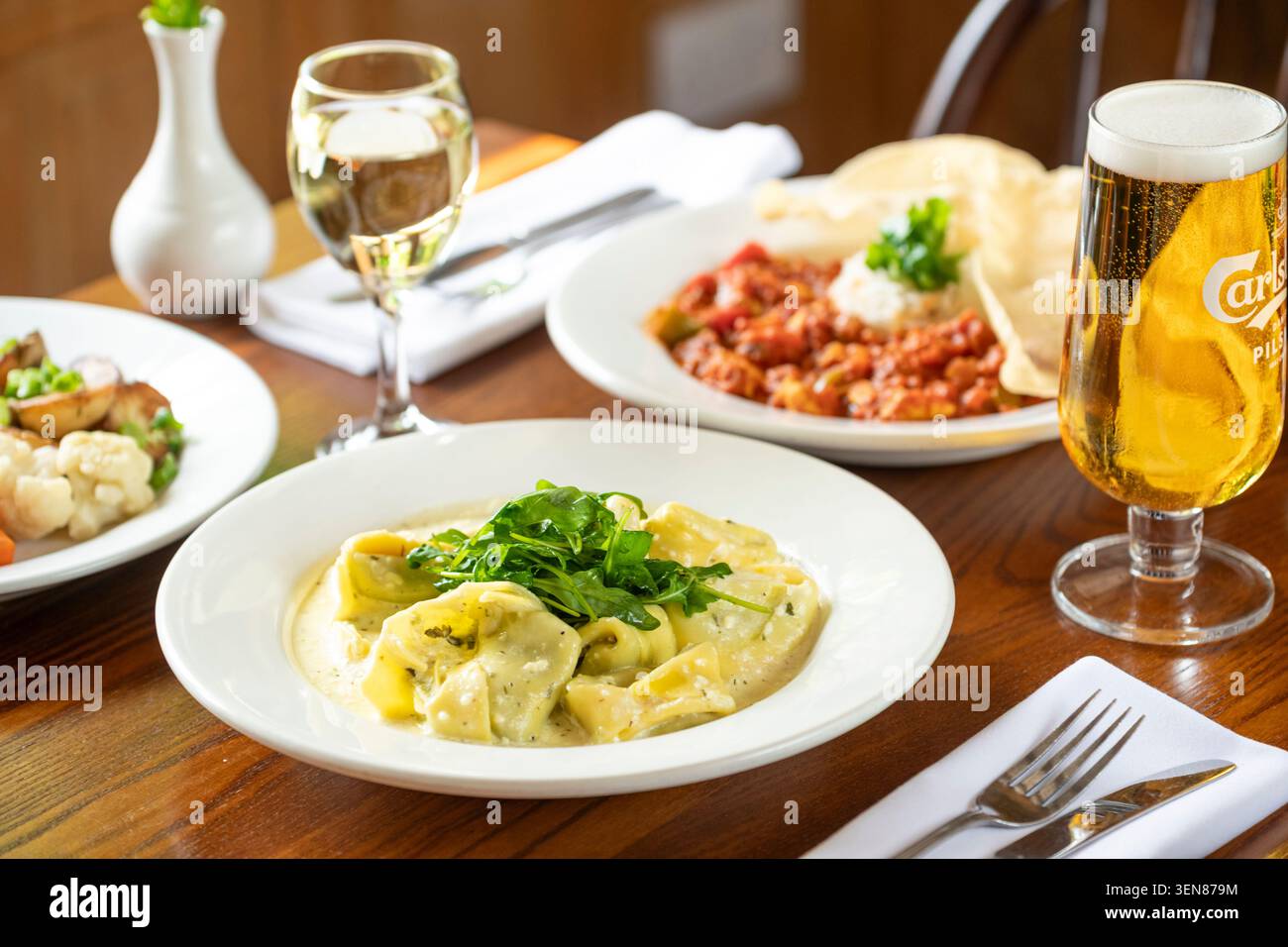 Köstliches Pasta-Gericht mit Wein und Bier in gemütlicher Atmosphäre Stockfoto