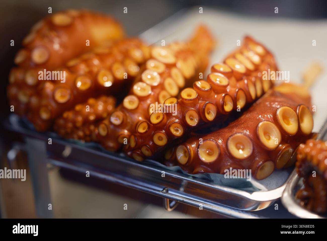 Ein Teller mit frisch gekochten, goldbraun glasierten ganzen Kraken-Tentakeln auf einem Straßenmarkt in Tokio, Japan Stockfoto