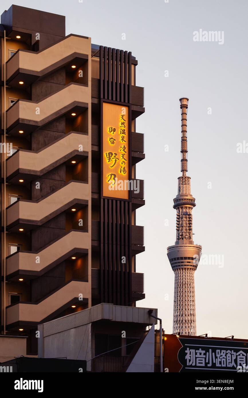 Ein abendlicher Blick auf den Tokyo Skytree erhebt sich vor einem weichen, verblassten Himmel, der von nahe gelegenen Apartmenthäusern eingerahmt wird, wenn das Tageslicht vergeht. Stockfoto