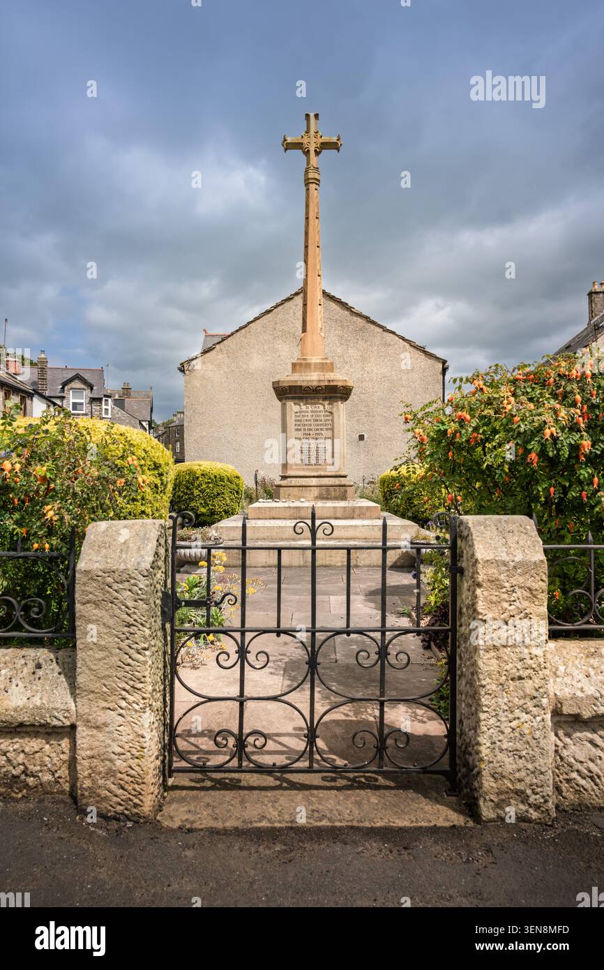 Symmetrischer Portraitblick mit Blick durch ein offenes eisernes Tor zum hohen Steinmauerkreuz des Dorfes in Tideswell, Peak District Stockfoto