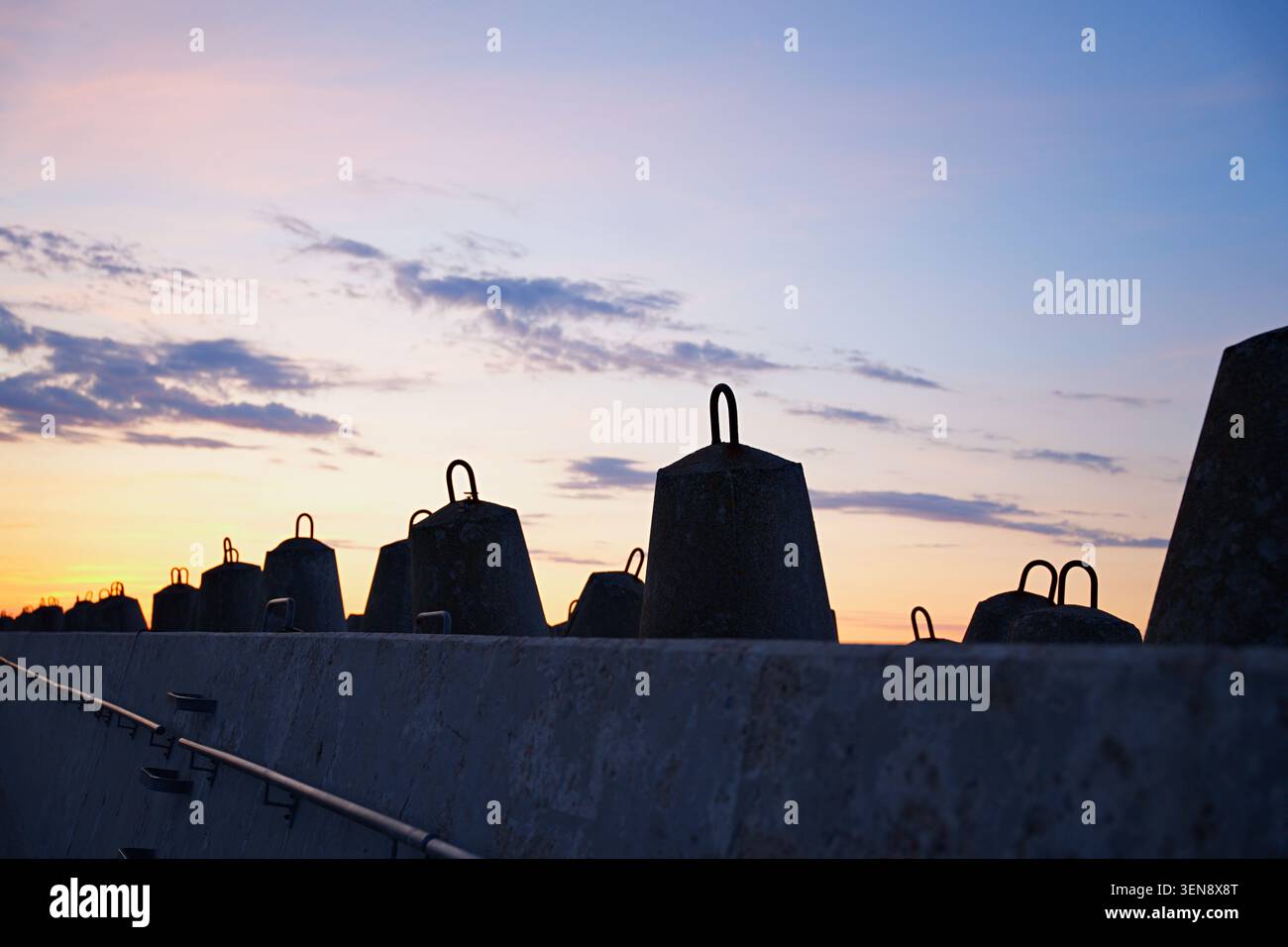 Beton-Tetrapoden, die als Wellenbrecher gegen den Sonnenuntergang verwendet wurden. Hochwertige Fotos Stockfoto